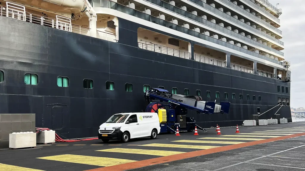 Mobiele stroominstallatie naast cruiseschip in haven voor walstroomvoorziening.